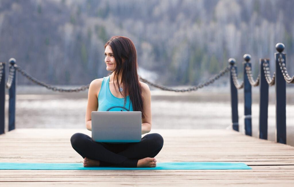 Woman thinking while on her laptop after Pilates mat exercise