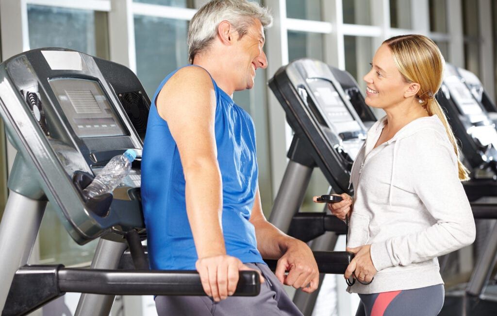 Female trainer working with male client on treadmill fitness