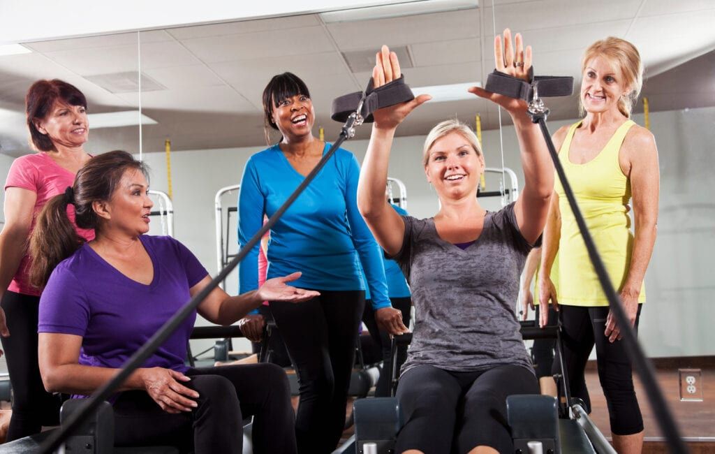 Group of enthusiastic women in Pilates reformer class learning