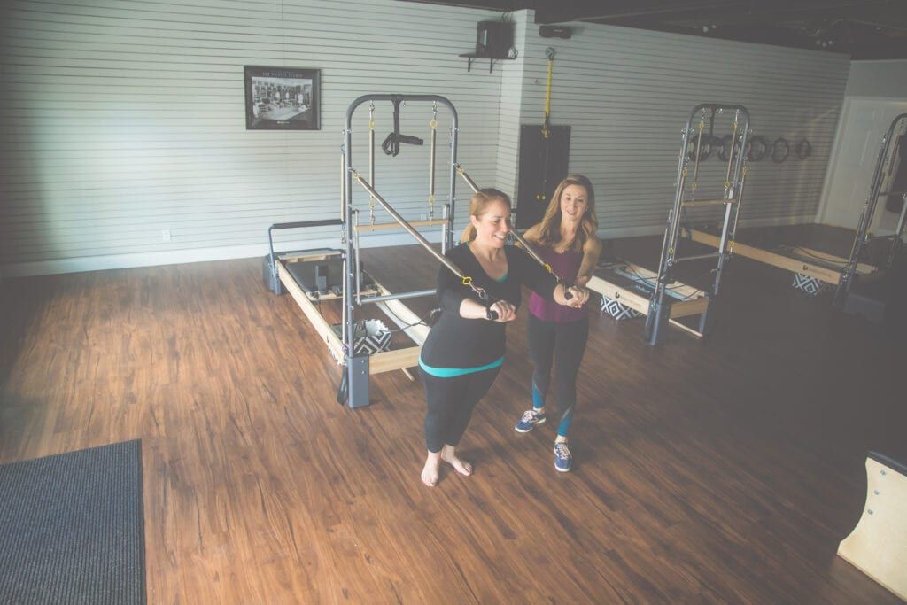 Laurie Sindlinger, Pilates instructor helping her client during Pilates exercises inside her studio