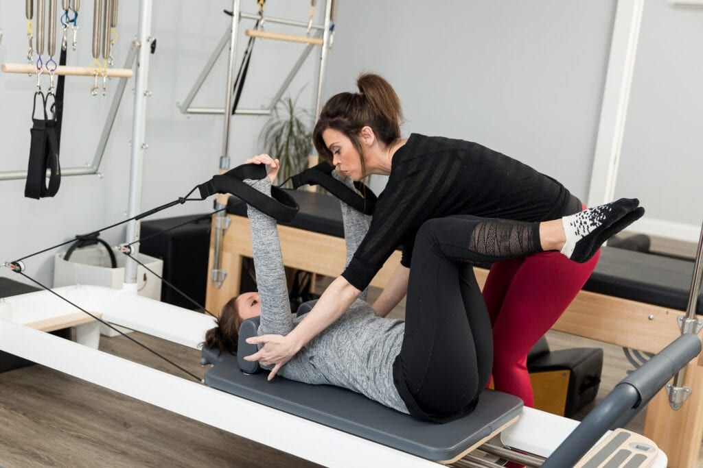 Nadine Taylor, Pilates instructor assisting her client during Pilates exercises on the Reformer