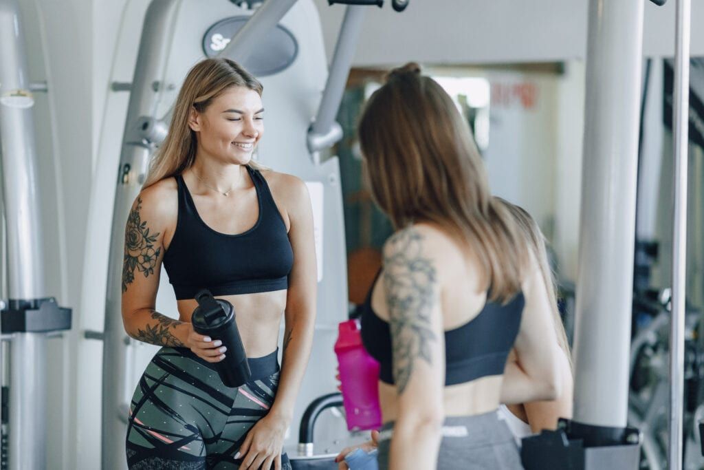 Female Pilates fitness instructors smiling and chatting with each other in the gym/studio