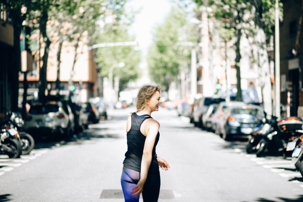 Woman walking happily after workout down a street